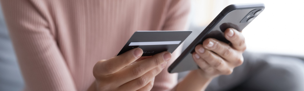 woman holding her phone and credit card making an online payment